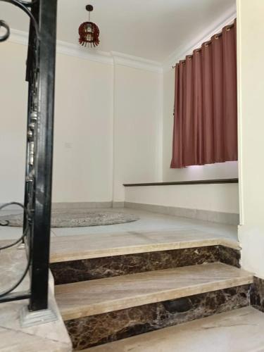 a room with a shower with wooden steps and a red curtain at Villa Standalone at Stella Heights North Coast in Sīdī ‘Abd ar Raḩmān