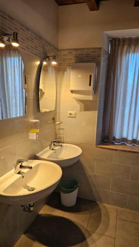 a bathroom with two sinks and a mirror at Ostello Cartiera La Buca in Colle di Val d'Elsa