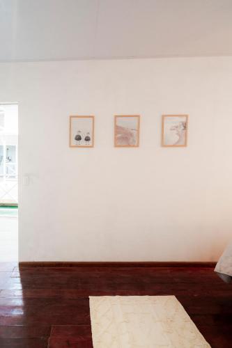 a white wall with four pictures on it at La Caribena Beach House- Bocas del Toro, Isla Colón, Panamá in Big Creek