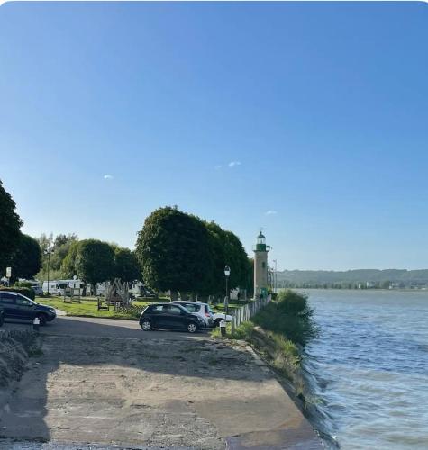two cars parked next to a river with a lighthouse at Ancienne maison de pêcheur atypique in Quillebeuf-sur-Seine