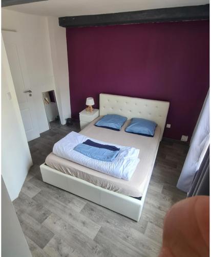 a bedroom with a white bed with blue pillows at Ancienne maison de pêcheur atypique in Quillebeuf-sur-Seine