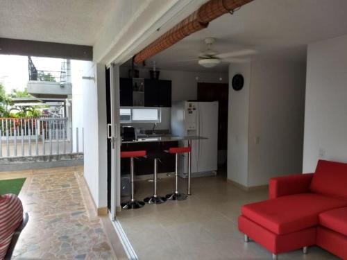a living room with a red couch and a kitchen at occidente Santa Fe de Antioquia sol y playa in Santa Fe de Antioquia