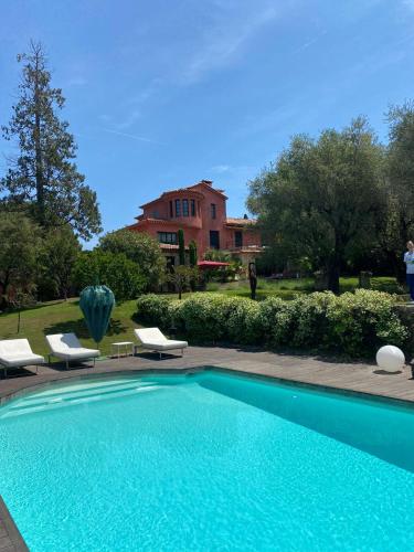 une piscine avec des chaises et une maison en arrière-plan dans l'établissement Charming Villa, à Mougins