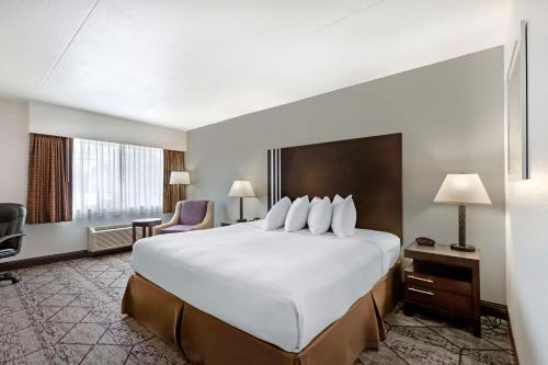 a hotel room with a large white bed and a chair at Best Western Plus Longbranch Hotel & Convention Center in Cedar Rapids