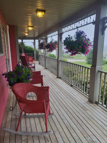 a porch with chairs and flowers on a house at Cranberry Cove Inn in Louisbourg