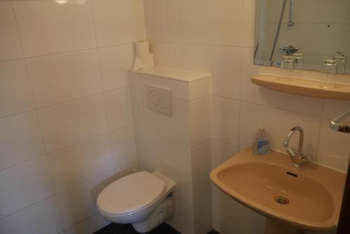 Baño blanco con aseo y lavamanos en Hotel Galerij, en Ámsterdam