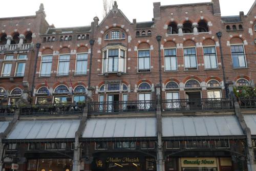 アムステルダムにあるホテル ギャラリーの大きなレンガ造りの建物で、窓とバルコニーが付いています。