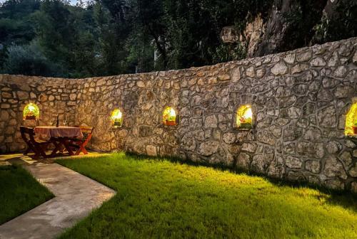 a stone wall with a table and a bench in a yard at Cozy Karuč Home in Cetinje