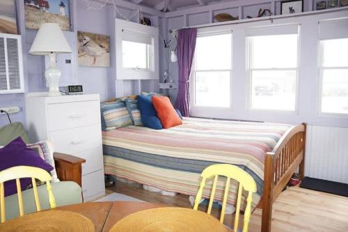 a bedroom with a bed and two yellow chairs at Peaceful Waterfront Beach Cottage! in Truro