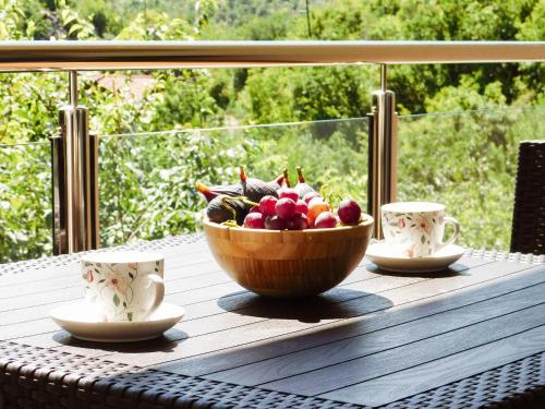 a bowl of fruit sitting on a table with two cups at Cozy Karuč Home in Cetinje