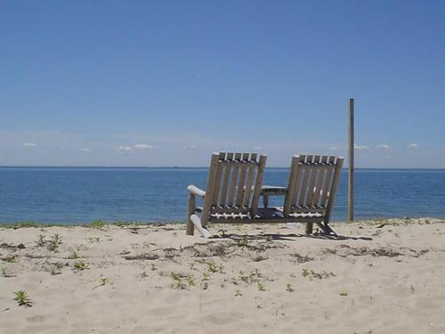 two benches sitting on the beach near the water at Cozy Beach Bungalow in Truro