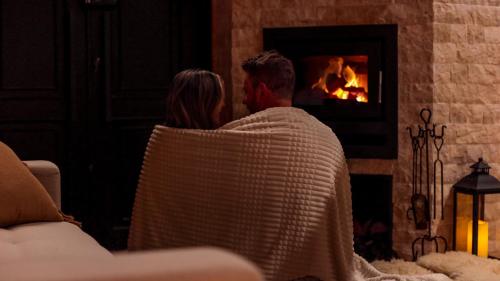a man and a woman sitting in a chair in front of a fireplace at SEGREDO do VALLE - BOSQUE in Urubici