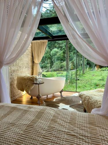 a bath tub in a bedroom with a window at SEGREDO do VALLE - BOSQUE in Urubici