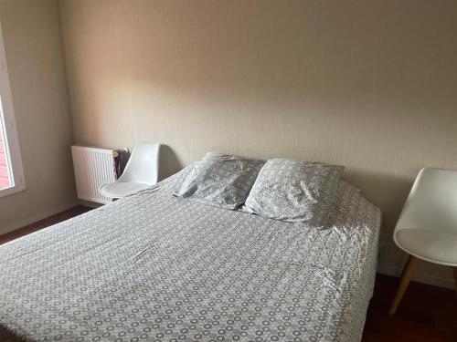 ein Schlafzimmer mit einem Bett und zwei weißen Stühlen in der Unterkunft Appartement 2 chambres in Artigues-près-Bordeaux