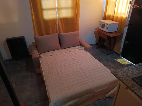 a small bed in a room with a microwave at VMdormis in Neuquén