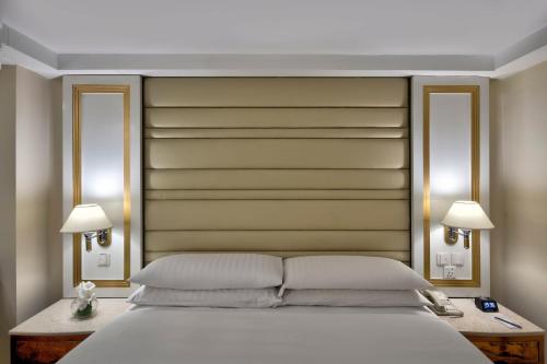 a bedroom with a large white bed with two lamps at Islamabad Marriott Hotel in Islamabad
