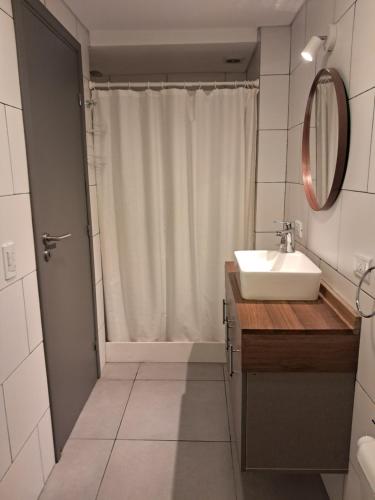 a bathroom with a sink and a shower with a mirror at Depto Los Pinos in Ostende