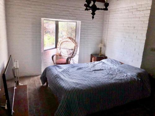 a bedroom with a bed and a chair and a window at Púrpura Atardecer Hermosa casa de montaña in San Javier