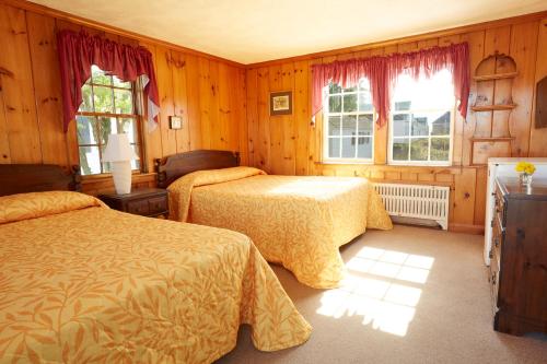 a bedroom with two beds and two windows at Kalmar Village & Tradewinds in North Truro