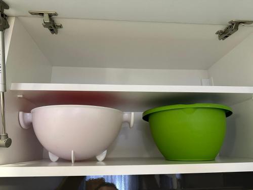 a green bowl and a white bowl on a shelf at Sunrise apartment in Podgorica