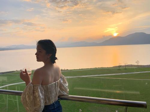 a woman standing on a balcony with a view of a lake at Huangshan Taiping Lake Muxin Hotel in Fenghuangshan