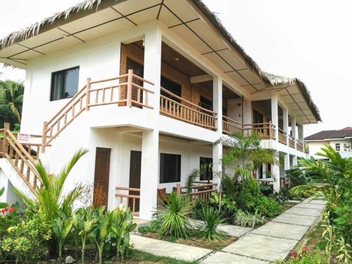 a white house with a balcony and plants at Sevens Hideaway Beach Resort in Siaton