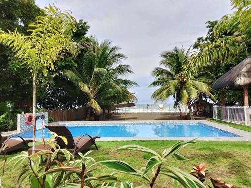 a swimming pool in a yard with palm trees at Sevens Hideaway Beach Resort in Siaton