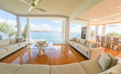 a living room with a view of the ocean at Bundeena Waterfront Pavilion in Bundeena