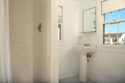 a white bathroom with a sink and a shower at Kalmar Village & Tradewinds in North Truro