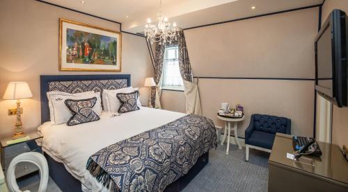 a bedroom with a bed and a table and a window at The Old Government House Hotel & Spa in St Peter Port