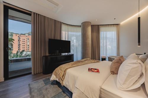 a bedroom with a large bed and a television at Nock - Reserved Residences in Medellín