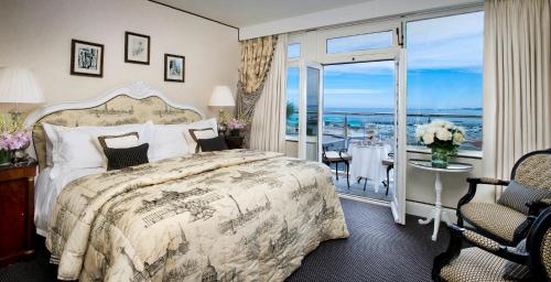 a bedroom with a large bed and a balcony at The Old Government House Hotel & Spa in St Peter Port