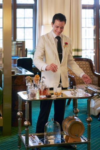 a man in a suit standing next to a table with glasses at Milestone Hotel Kensington in London