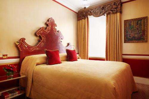 a bedroom with a large bed with red pillows at Milestone Hotel Kensington in London