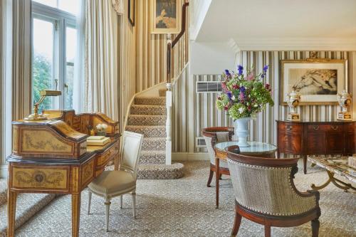 a living room with a desk and a table and stairs at Milestone Hotel Kensington in London