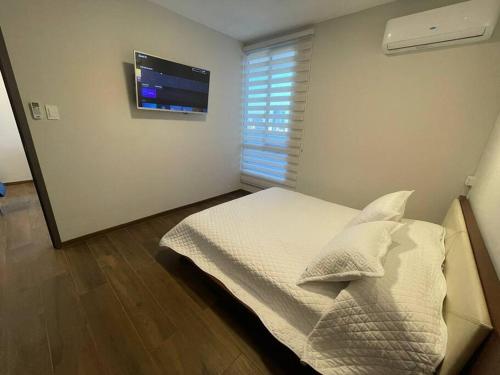 a bedroom with a bed with a television on the wall at Equipetrol Depto 1 Dorm piso 12 in Santa Cruz de la Sierra