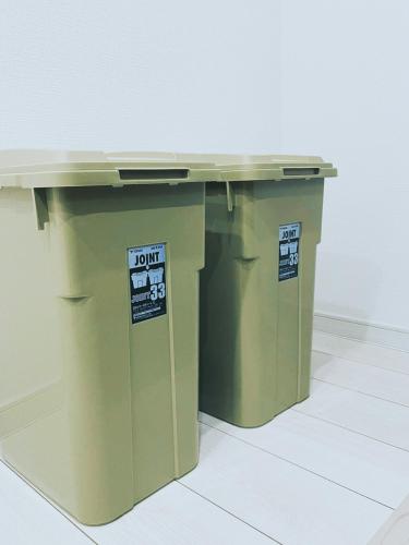 a green table with two trash cans underneath it at 下町立石駅近民泊美幸 in Tokyo