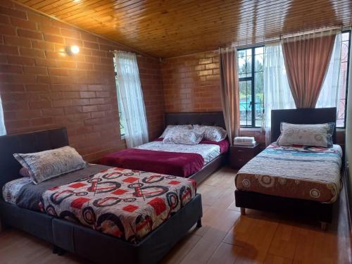 a bedroom with two beds and a brick wall at La casaaa de Majo in Paipa