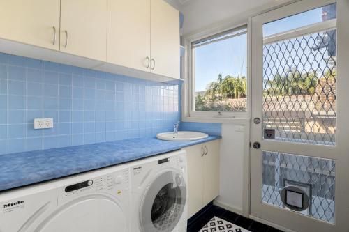 a laundry room with a washing machine and a window at 5-Bed Haven with Pool Minutes From Beaches & Parks in Beaumaris