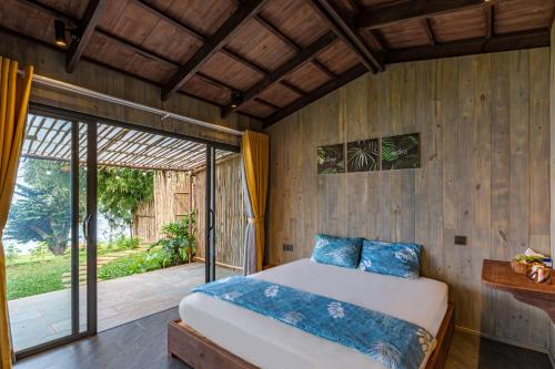 a bedroom with a bed and a sliding glass door at Nomia Garden Retreats - Khu nghỉ dưỡng hồ Trị An in Xóm Ðốt Ðó