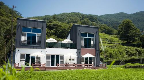 a house with chairs and umbrellas in front of it at Hadong Huige Stay Pension in Hadong