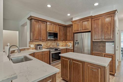 a kitchen with wooden cabinets and a stainless steel refrigerator at New!4BR with Easy Access to all Woodlands Amenities in The Woodlands