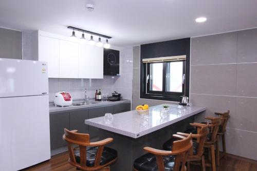 a kitchen with a white refrigerator and wooden chairs at Uljin Blue Ara B pension in Uljin