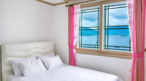 ein Schlafzimmer mit einem Bett und einem Fenster in der Unterkunft Geojae Beach Maru Pension in Geoje