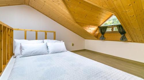 ein Schlafzimmer mit einem weißen Bett und einer Holzdecke in der Unterkunft Geojae Beach Maru Pension in Geoje