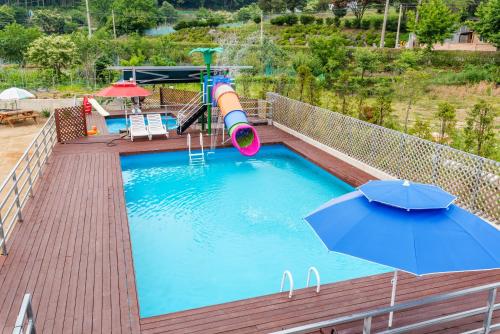 a pool with a water slide and an umbrella at Marine Pension Paju in Paju