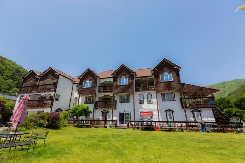 a large building with a grass field in front of it at Muju Snow Country Pension in Muju
