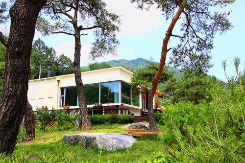 a house in the middle of a field with trees at Yangpyeong Sanneomeo Pension in Yangpyeong