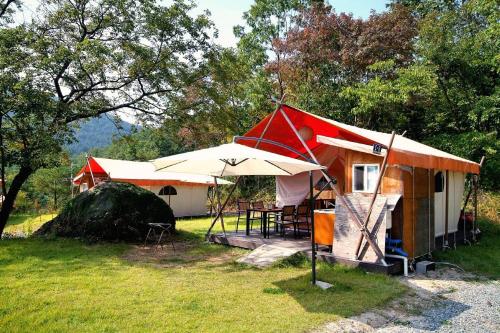 a small tent with a table and an umbrella at Pocheon Sanjeong Hosoo Glamping in Pocheon