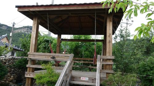 a wooden gazebo with a swing at Buan sukranjeong pension in Buan